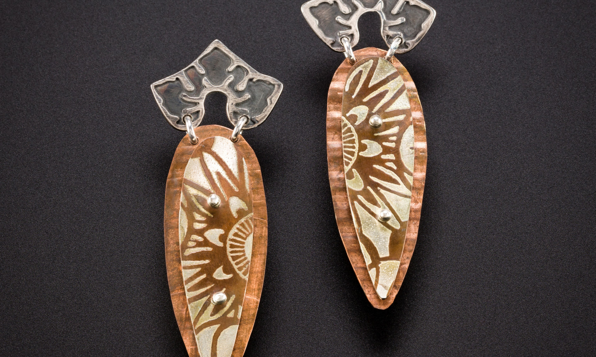 pair of earrings by Julie Packer on a dark background