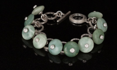 Seafoam and other light green jade stones with silver centers on handmade silver bracelet by Carol Holaday