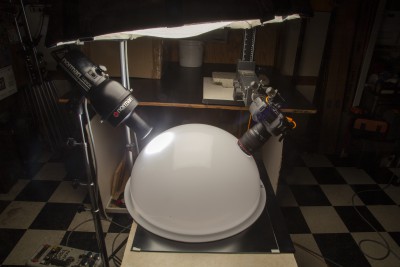 White acrylic Cloud Dome setup with 2 holes at 45 degree angles to the object in the dome; one hole has spotlight and 2nd hole has camera lens