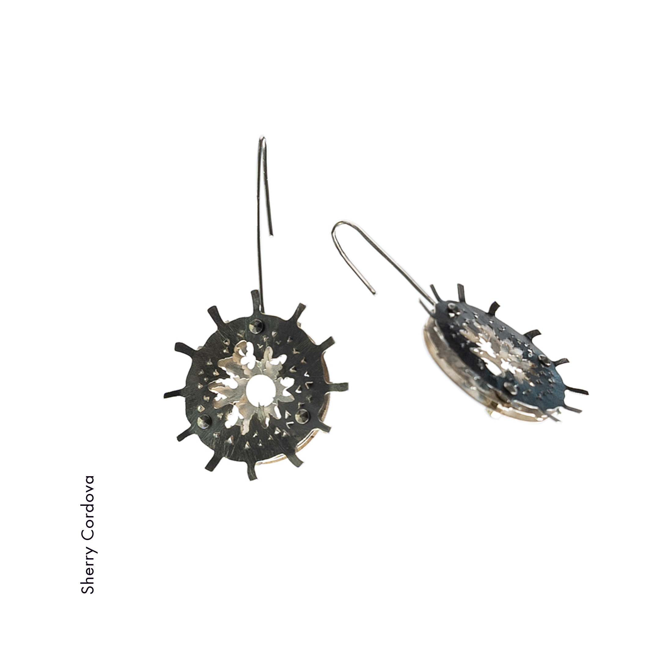 Sherry Cordova made these earrings using 3 layers of argentium sterling silver which form a radiolaria. The top layer is patinated dark to highlight the bottom two layers. The niobium ear wires and stainless steel fasteners add an industrial touch to the organic shapes