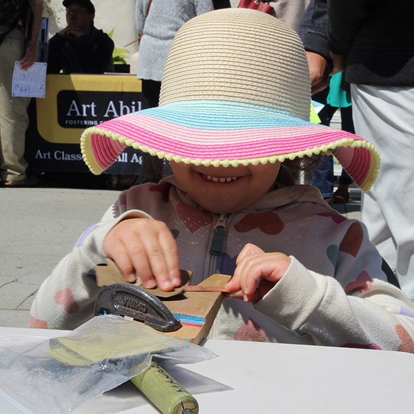 True joy while sanding a copper strip to create a bracelet at the Make A Bracelet event as part of the Monterey Museum of Art Block Party 2023
